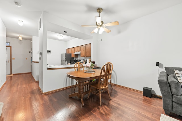 dining space with ceiling fan, sink, and wood-type flooring