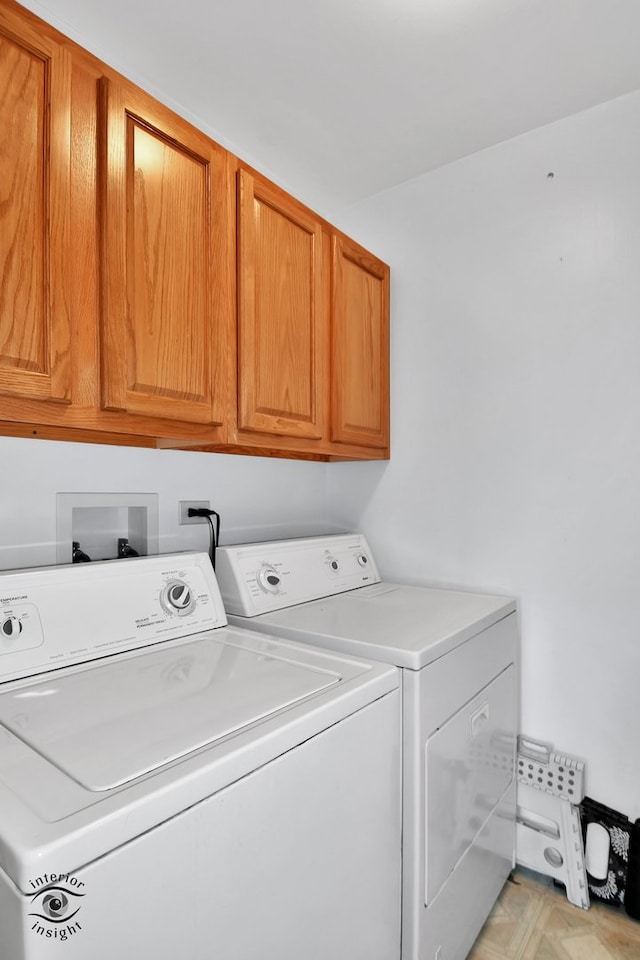 clothes washing area featuring washer and clothes dryer and cabinets