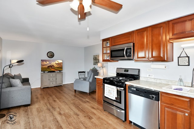 kitchen with ceiling fan, sink, stainless steel appliances, and light wood-type flooring