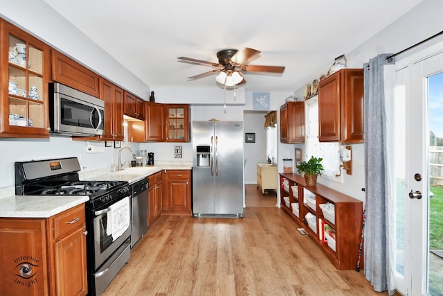 kitchen featuring ceiling fan, sink, stainless steel appliances, and light wood-type flooring