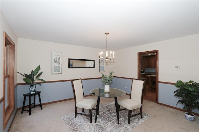 carpeted dining space featuring an inviting chandelier