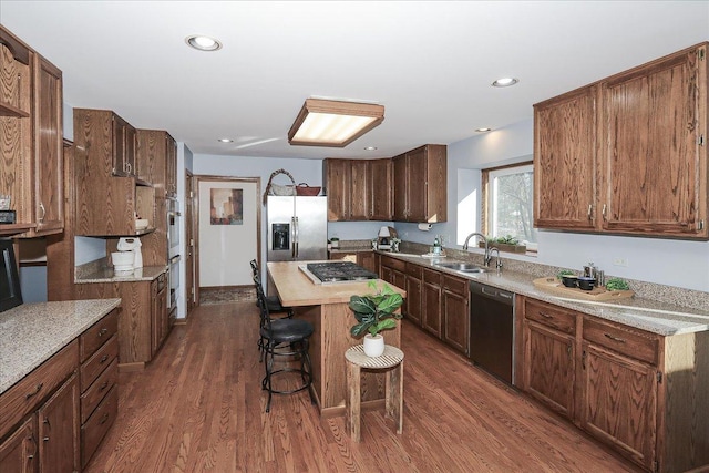 kitchen with dark hardwood / wood-style flooring, sink, a breakfast bar, a kitchen island, and stainless steel appliances