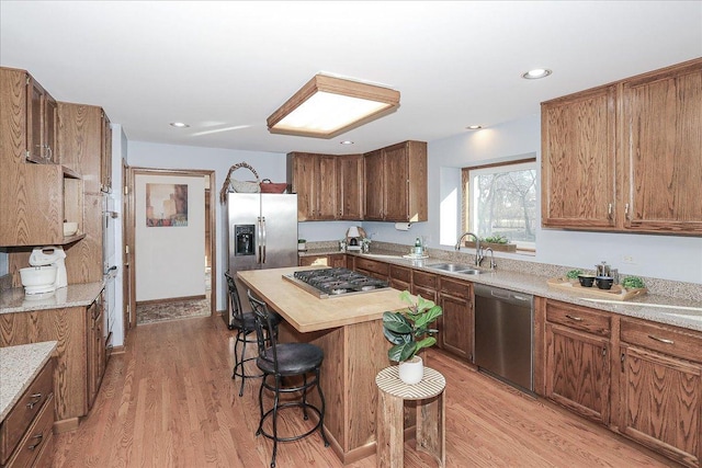 kitchen featuring a center island, sink, light hardwood / wood-style flooring, stainless steel appliances, and a breakfast bar area