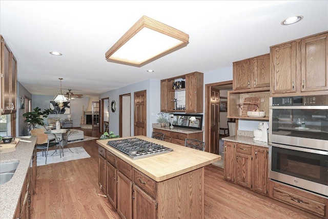 kitchen featuring hanging light fixtures, appliances with stainless steel finishes, sink, a kitchen island, and light hardwood / wood-style floors