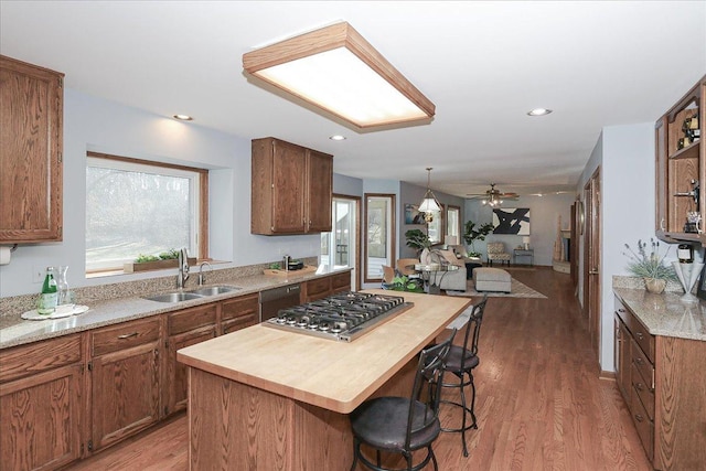 kitchen featuring a kitchen breakfast bar, sink, dark hardwood / wood-style floors, a kitchen island, and stainless steel gas cooktop