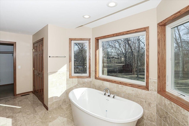 bathroom with a bath and tile walls