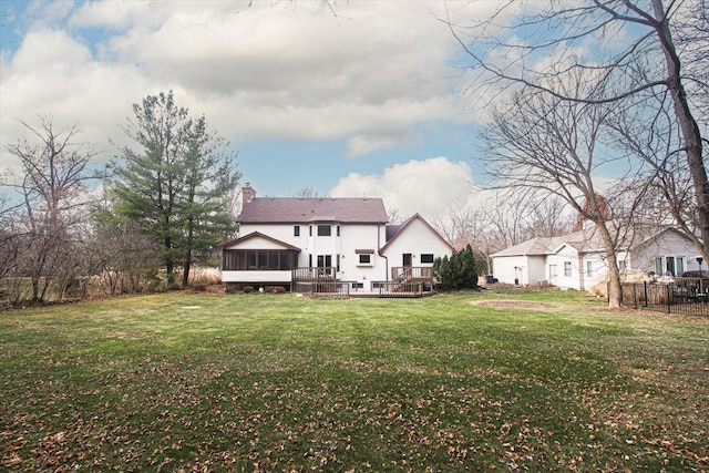 rear view of house with a deck, a lawn, and a sunroom