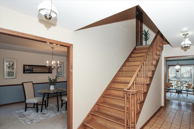 stairway with tile patterned floors and an inviting chandelier