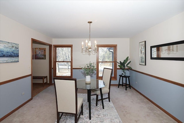 dining space featuring light carpet and an inviting chandelier