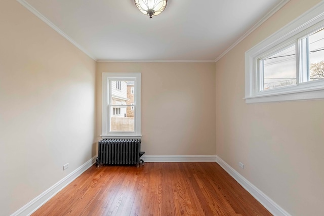 spare room with wood-type flooring, radiator heating unit, and ornamental molding