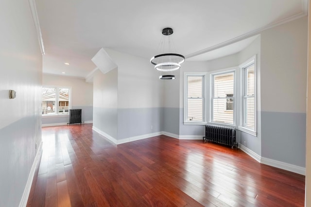 unfurnished room featuring radiator heating unit, dark hardwood / wood-style floors, an inviting chandelier, and ornamental molding