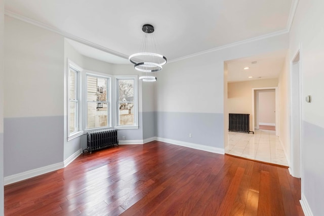 spare room with radiator heating unit, a notable chandelier, crown molding, and wood-type flooring