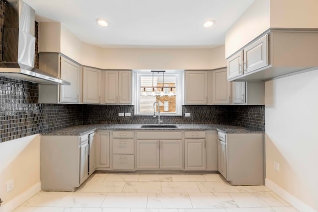 kitchen with decorative backsplash, gray cabinets, wall chimney exhaust hood, and sink