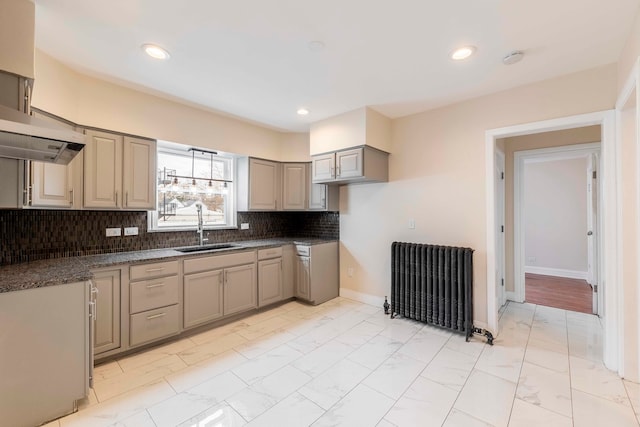 kitchen featuring tasteful backsplash, radiator, dark stone countertops, and sink