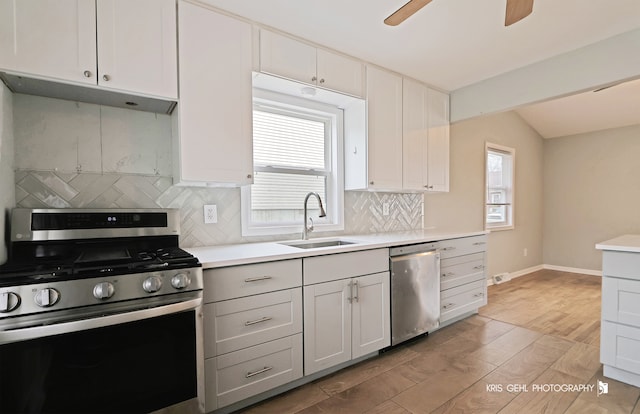 kitchen featuring lofted ceiling, white cabinets, sink, light wood-type flooring, and stainless steel appliances