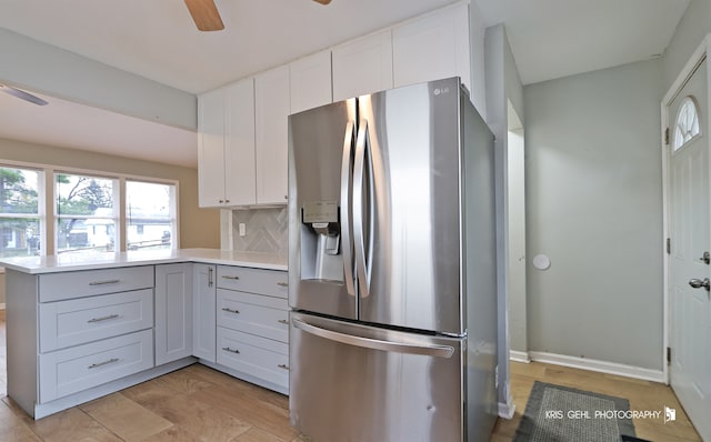 kitchen with tasteful backsplash, stainless steel fridge with ice dispenser, kitchen peninsula, light hardwood / wood-style floors, and white cabinets