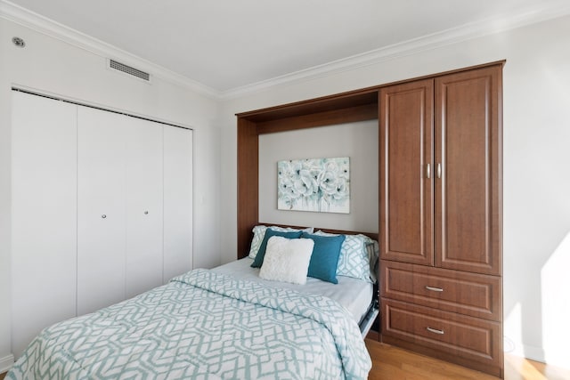 bedroom with light hardwood / wood-style floors, a closet, and ornamental molding