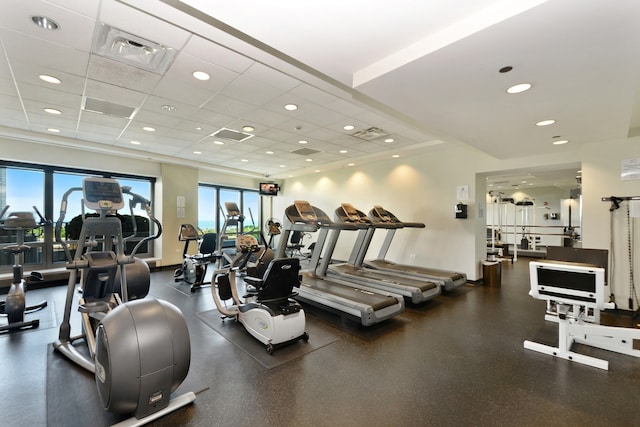 exercise room with a paneled ceiling and a wealth of natural light