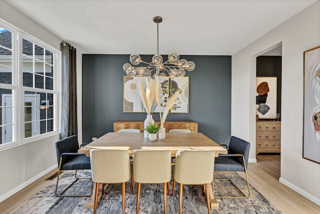 dining space featuring a notable chandelier and light wood-type flooring