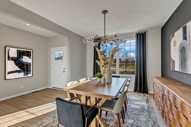 dining room with hardwood / wood-style floors and an inviting chandelier