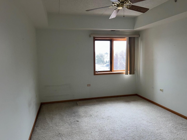 unfurnished room featuring a tray ceiling, ceiling fan, carpet floors, and a textured ceiling