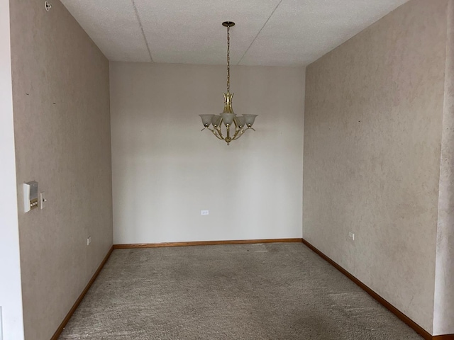 carpeted spare room with a notable chandelier