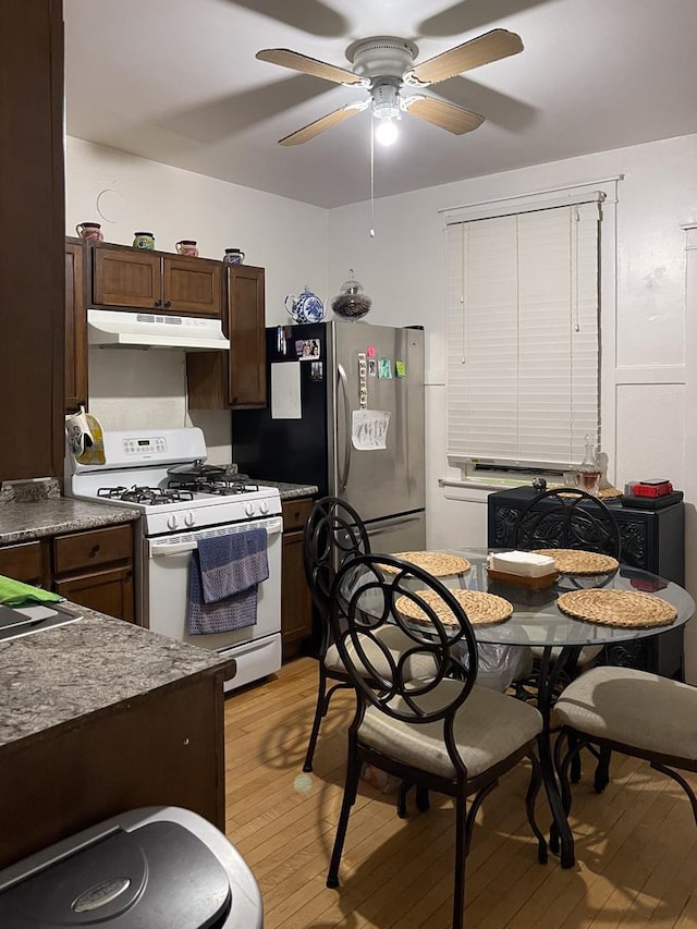 kitchen with light hardwood / wood-style flooring, ceiling fan, white range with gas cooktop, dark brown cabinets, and stainless steel refrigerator