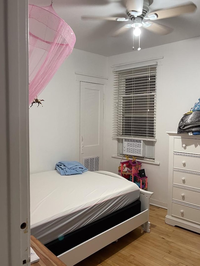 bedroom with hardwood / wood-style floors, ceiling fan, and cooling unit