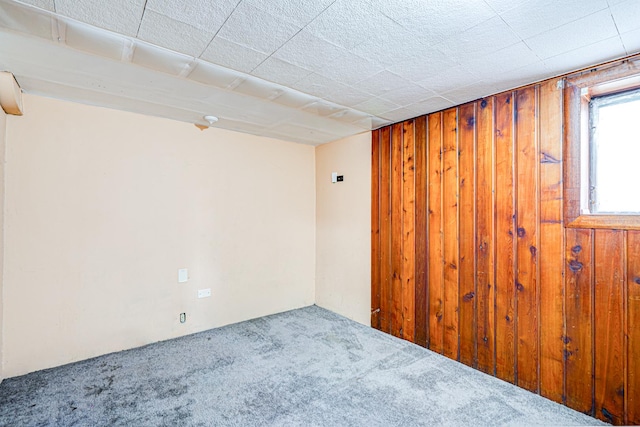 carpeted spare room featuring wooden walls