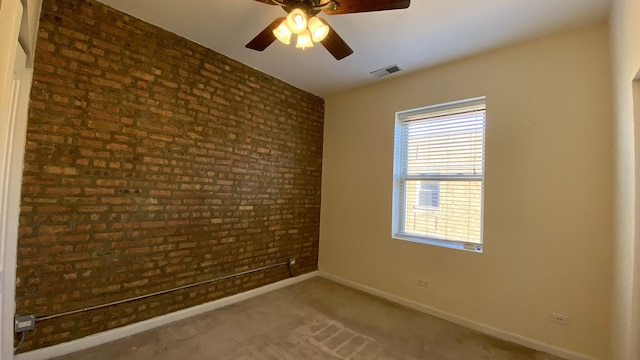 unfurnished room featuring carpet flooring, ceiling fan, and brick wall