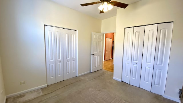 unfurnished bedroom featuring ceiling fan, light carpet, and two closets