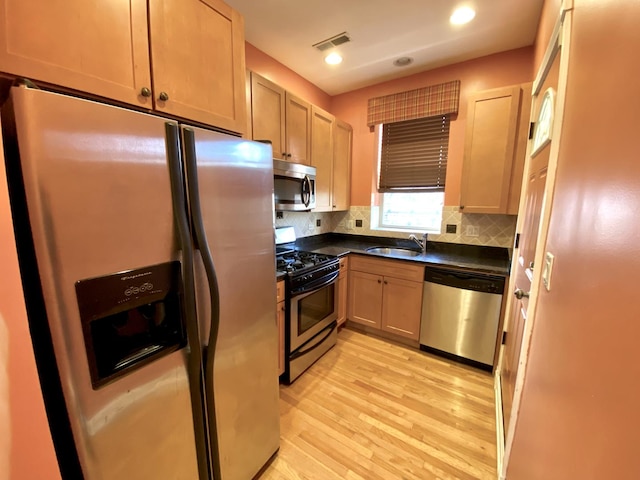 kitchen featuring appliances with stainless steel finishes, light wood-type flooring, tasteful backsplash, light brown cabinetry, and sink