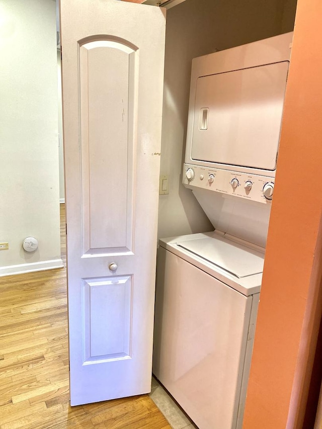 washroom featuring stacked washing maching and dryer and light hardwood / wood-style floors