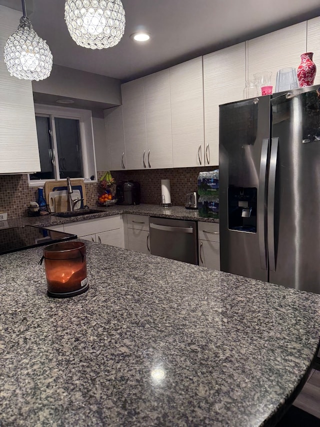 kitchen with dark stone countertops, stainless steel appliances, and decorative light fixtures