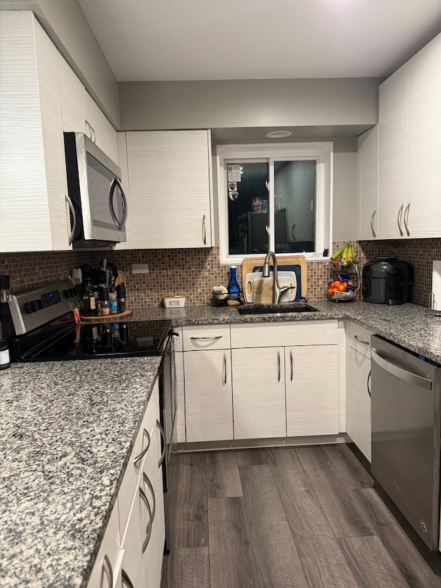 kitchen featuring dark stone counters, sink, dark wood-type flooring, and appliances with stainless steel finishes