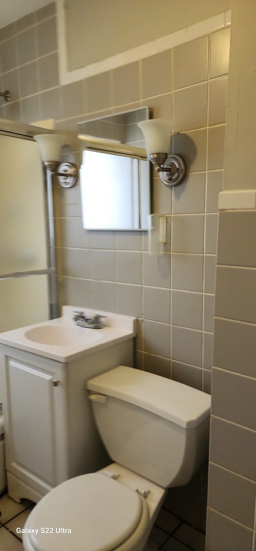 bathroom featuring tile patterned floors, sink, tile walls, and toilet