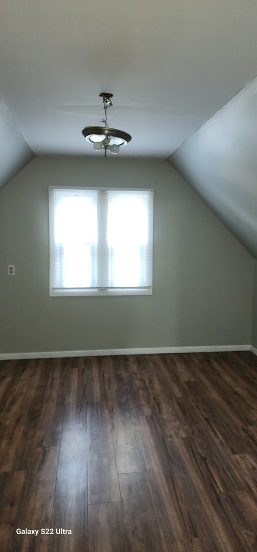 bonus room with lofted ceiling and dark wood-type flooring