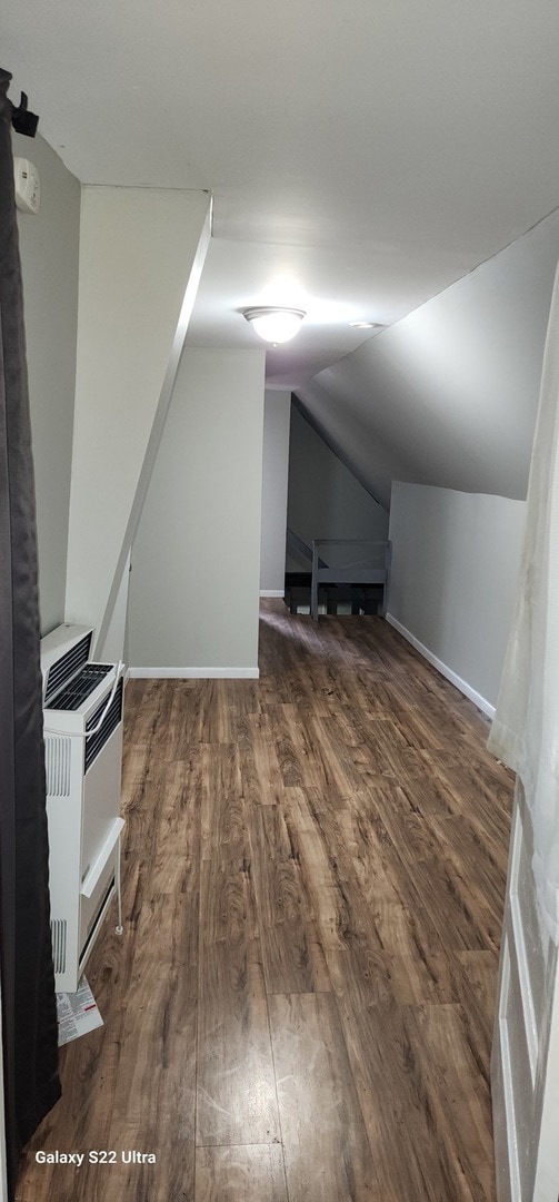 bonus room with dark hardwood / wood-style floors, lofted ceiling, and heating unit