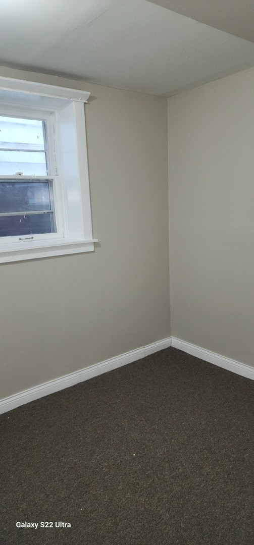 spare room featuring dark colored carpet