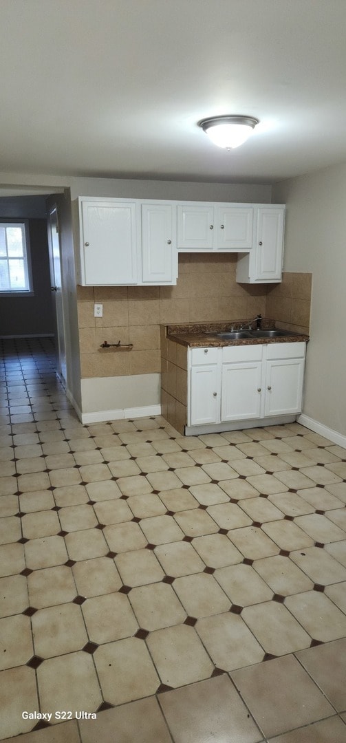 kitchen featuring decorative backsplash, sink, and white cabinets