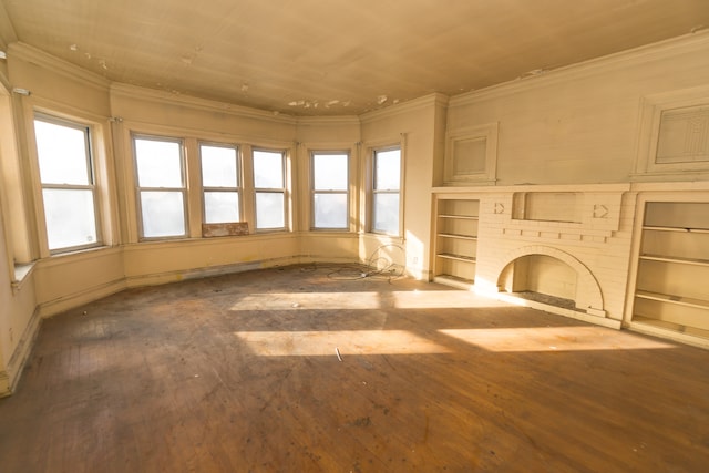 unfurnished living room featuring built in shelves, crown molding, a fireplace, and hardwood / wood-style flooring