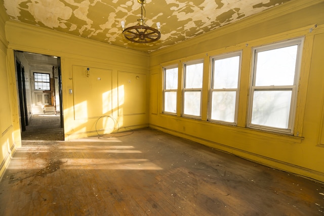 unfurnished room featuring dark wood-type flooring, an inviting chandelier, a wealth of natural light, and ornamental molding