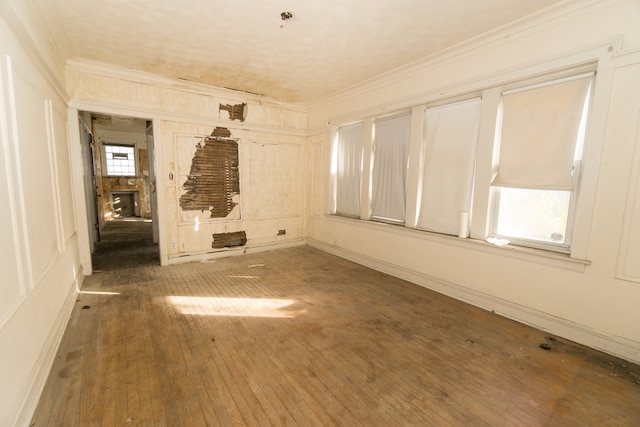 unfurnished room featuring dark hardwood / wood-style floors, a stone fireplace, and ornamental molding