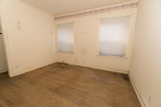 empty room with dark wood-type flooring and ornamental molding