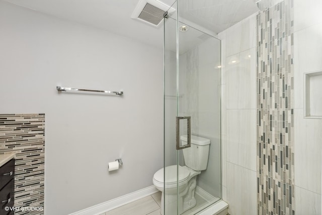 bathroom with tile patterned floors, vanity, an enclosed shower, and toilet