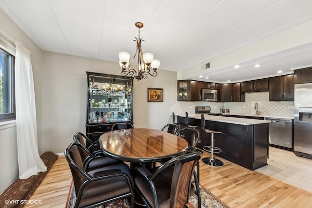 dining area featuring a chandelier, sink, and light hardwood / wood-style floors