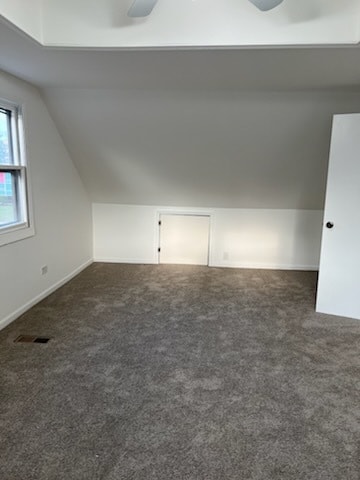 bonus room featuring dark colored carpet, vaulted ceiling, and ceiling fan