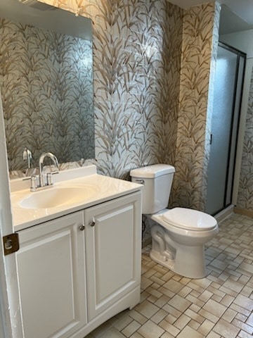 bathroom with vanity, toilet, and a shower with door