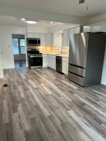 kitchen featuring appliances with stainless steel finishes, light wood-type flooring, ceiling fan, sink, and white cabinets