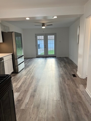 unfurnished living room with ceiling fan, french doors, and light wood-type flooring